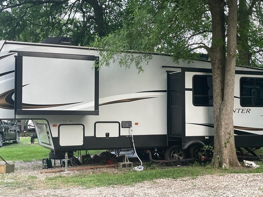 Furrion fifth-wheel RV with slide-out parked under oak trees at Sugar Land RV Park
