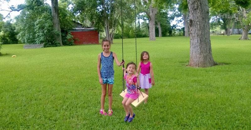 Children playing on a rope swing in the green lawn at Sugar Land RV Park