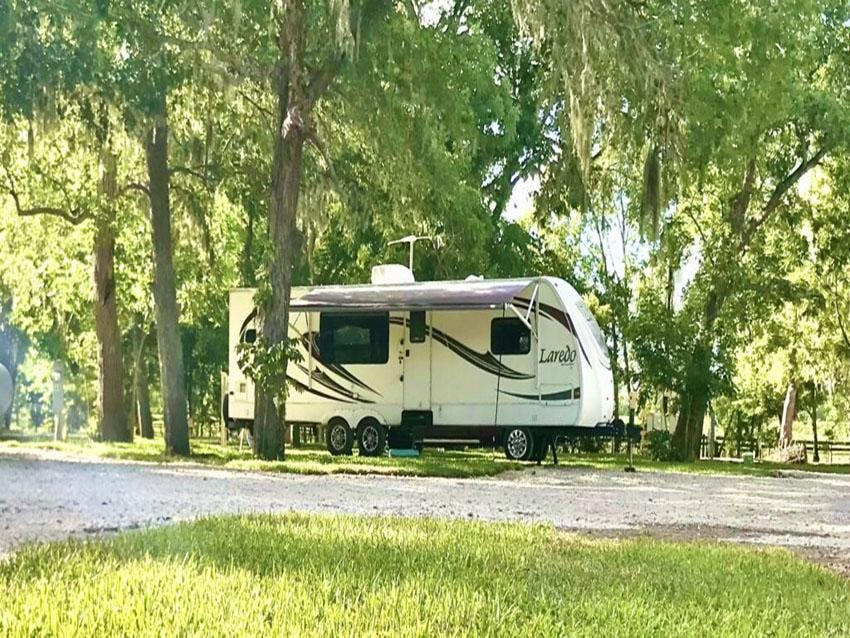 Laredo RV trailer parked under shaded trees at Sugar Land RV Park