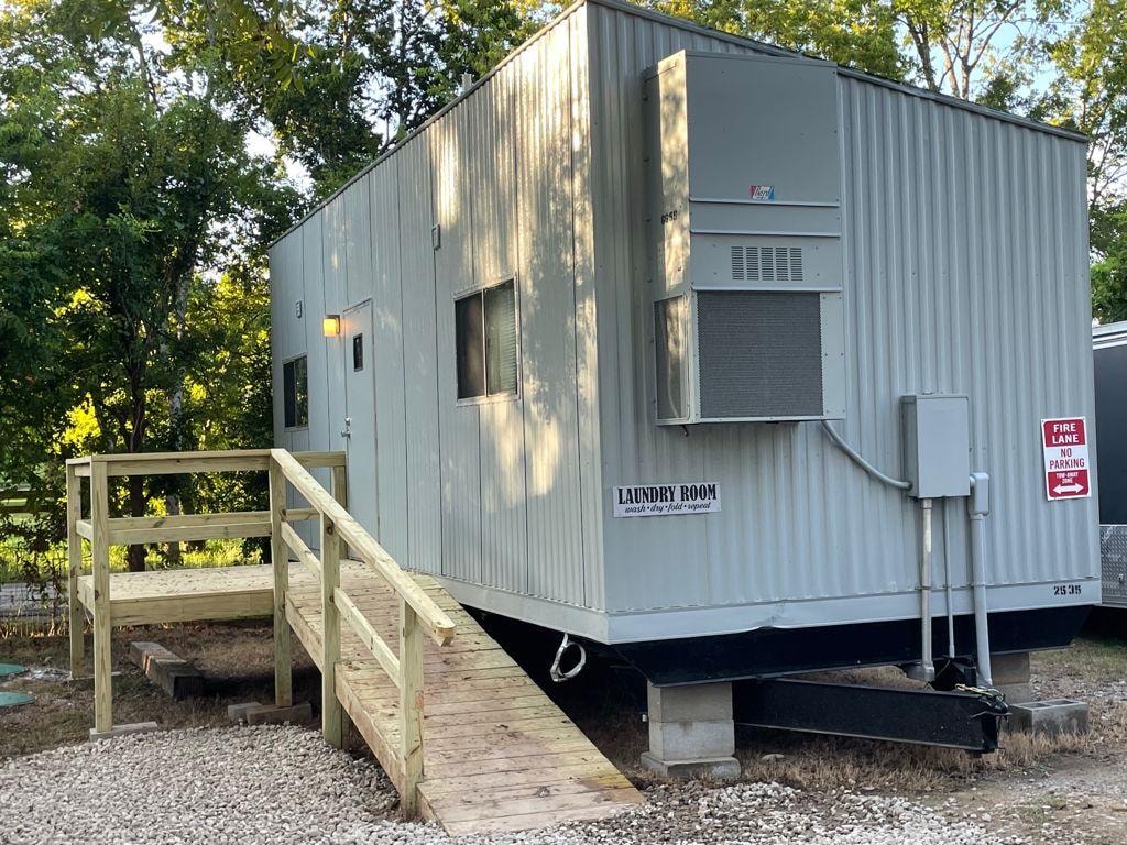 Laundry room building exterior with wooden ramp and Laundry Room sign at Sugar Land RV Park