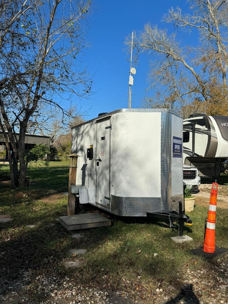 Managers Office trailer side view with satellite dish at Sugar Land RV Park
