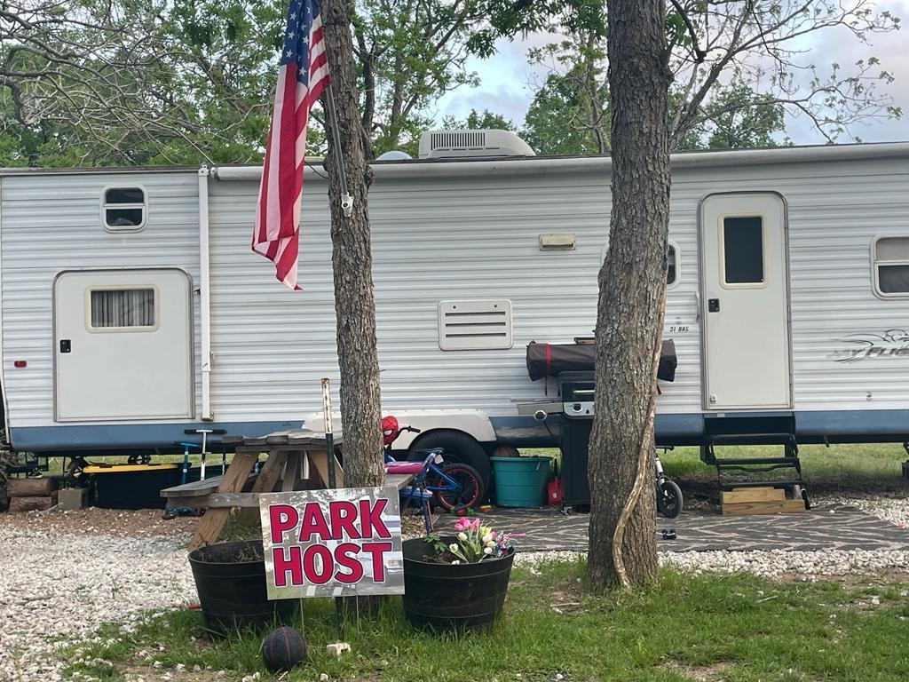 Park Host trailer with American flag and flower pots at Sugar Land RV Park