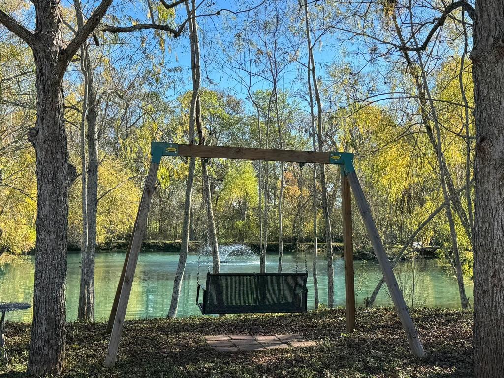 Wooden swing set overlooking the pond with fountain at Sugar Land RV Park