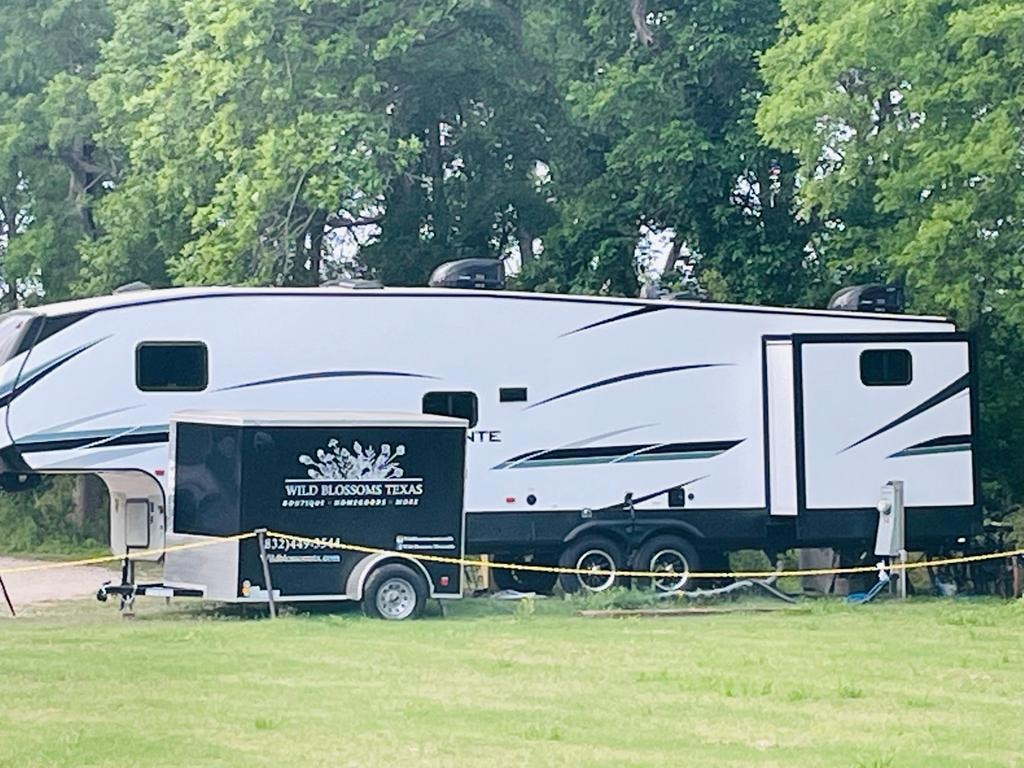 Large fifth-wheel RV with Wild Blossoms Texas vendor trailer at Sugar Land RV Park